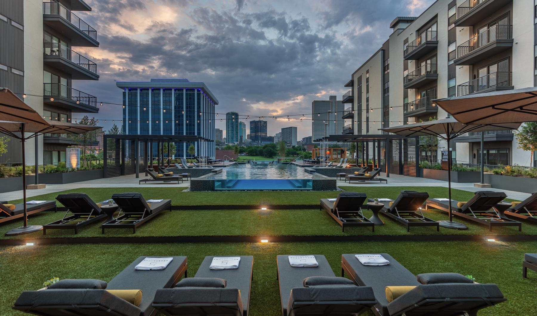 a pool in a courtyard with many lounge chairs